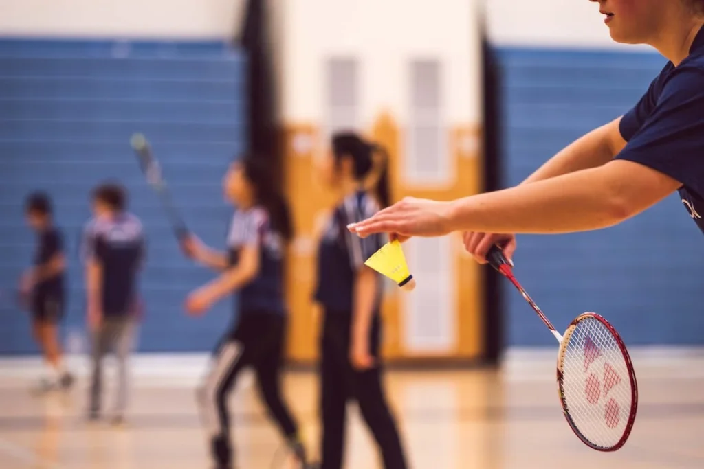 A badminton player executes a powerful spin serve, creating spin and deception with a swift swing of the racket.