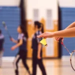 A badminton player executes a powerful spin serve, creating spin and deception with a swift swing of the racket.