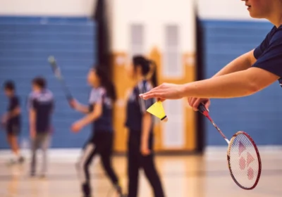 A badminton player executes a powerful spin serve, creating spin and deception with a swift swing of the racket.